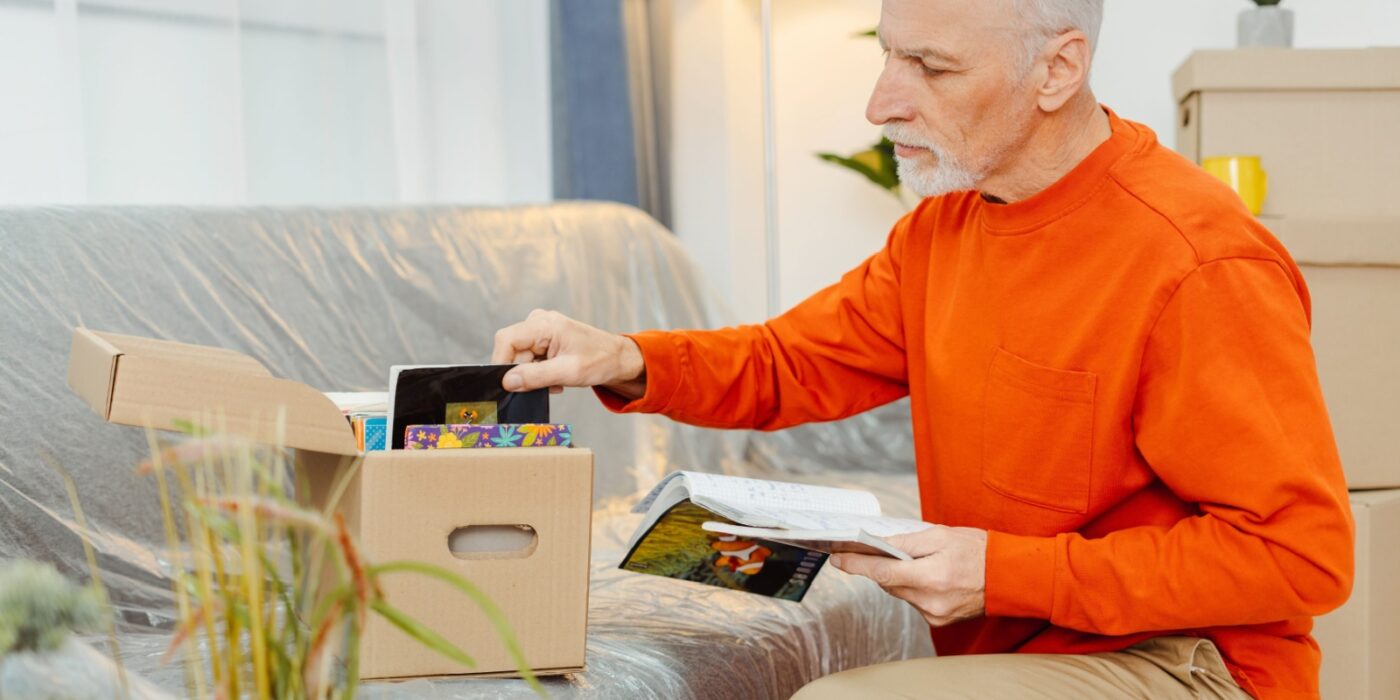 A senior packs a small box of photos to take to the senior living community.