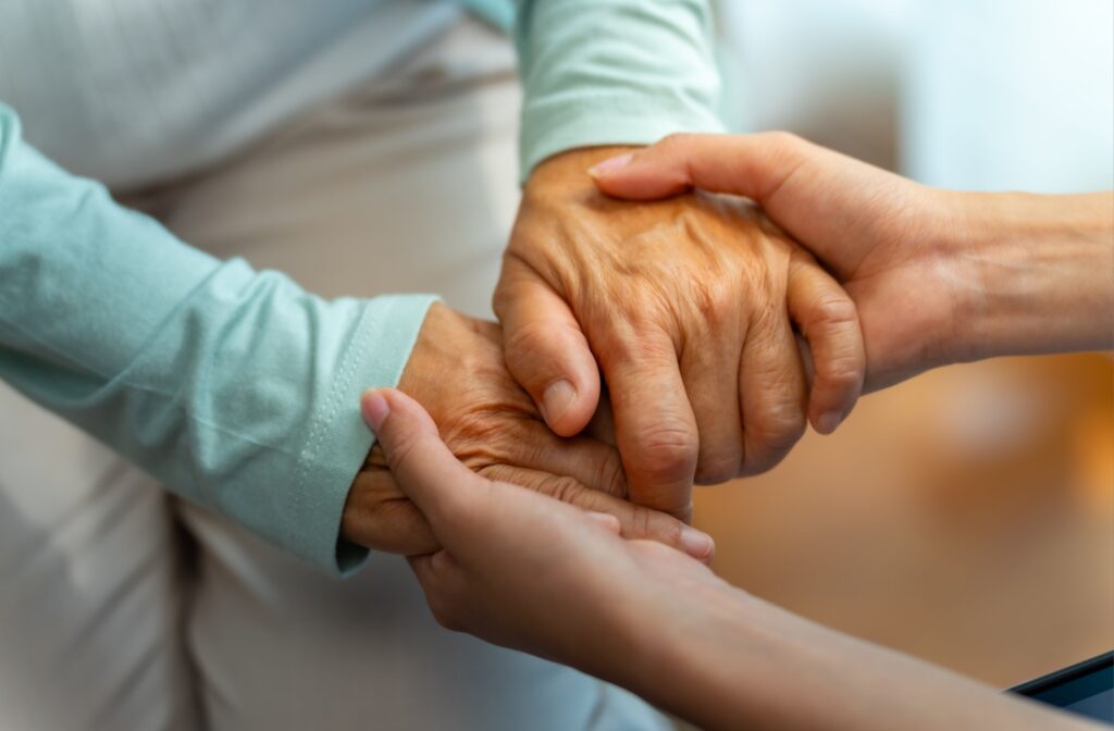 A close up of an older woman's hands being held by a younger woman.