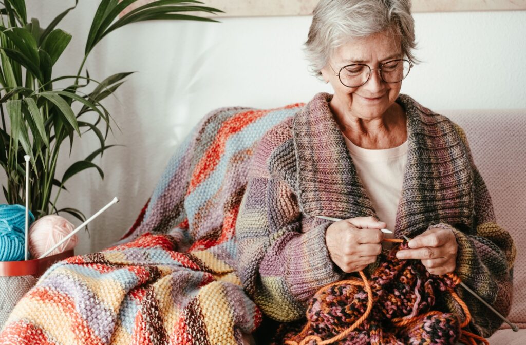 A senior in an assisted living community happily knitting