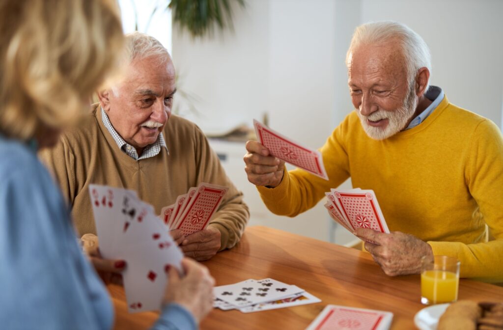 Seniors enjoying a lively card game together, smiling and engaged in a social activity.