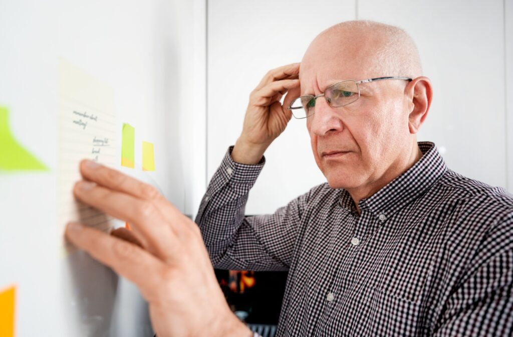An elderly man looking at a note on the board and struggling to remember what it meant.