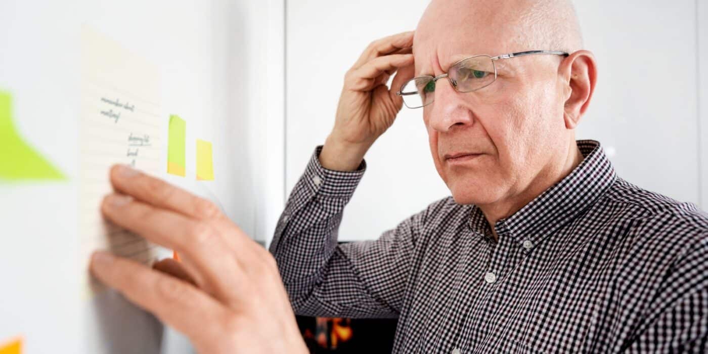 An elderly man looking at a note on the board and struggling to remember what it meant.
