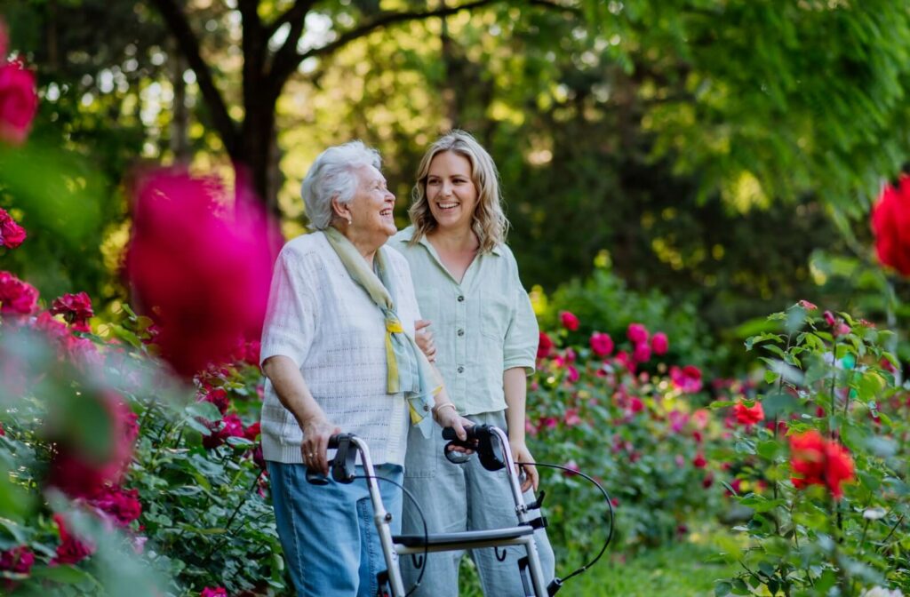 A senior woman with a walker enjoying time in a park with her daughter.