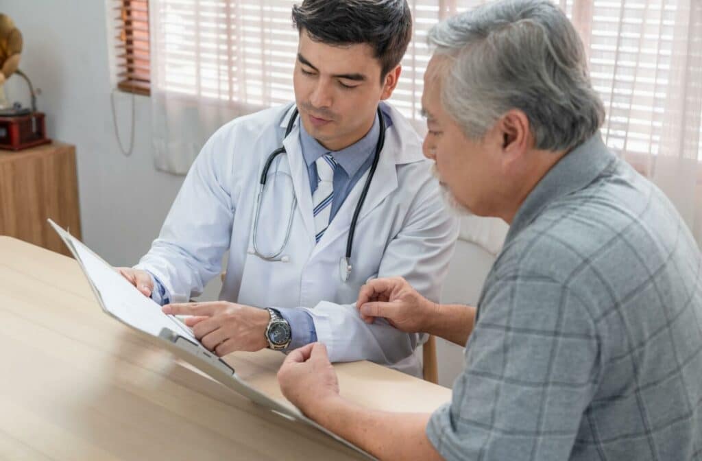 Doctor showing medical chart to older adult during a health consultation at a clinic table