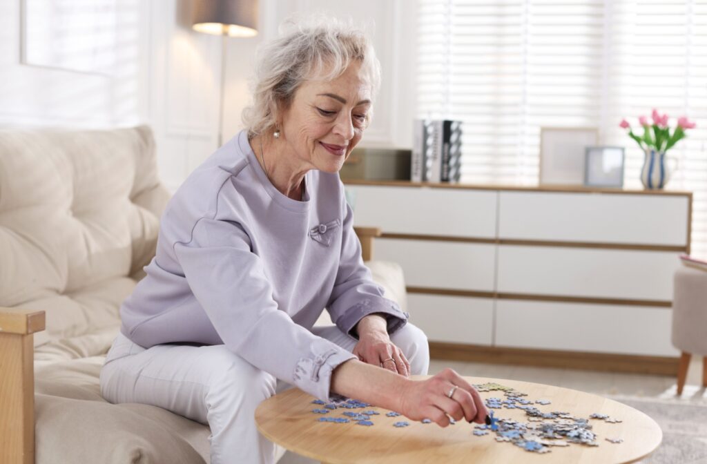 A senior smiles as they sort through the pieces of a puzzle meant to help support their cognitive thinking in memory care