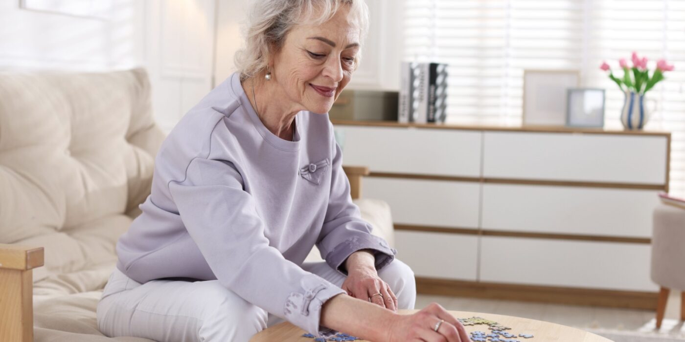 A senior smiles as they sort through the pieces of a puzzle meant to help support their cognitive thinking in memory care