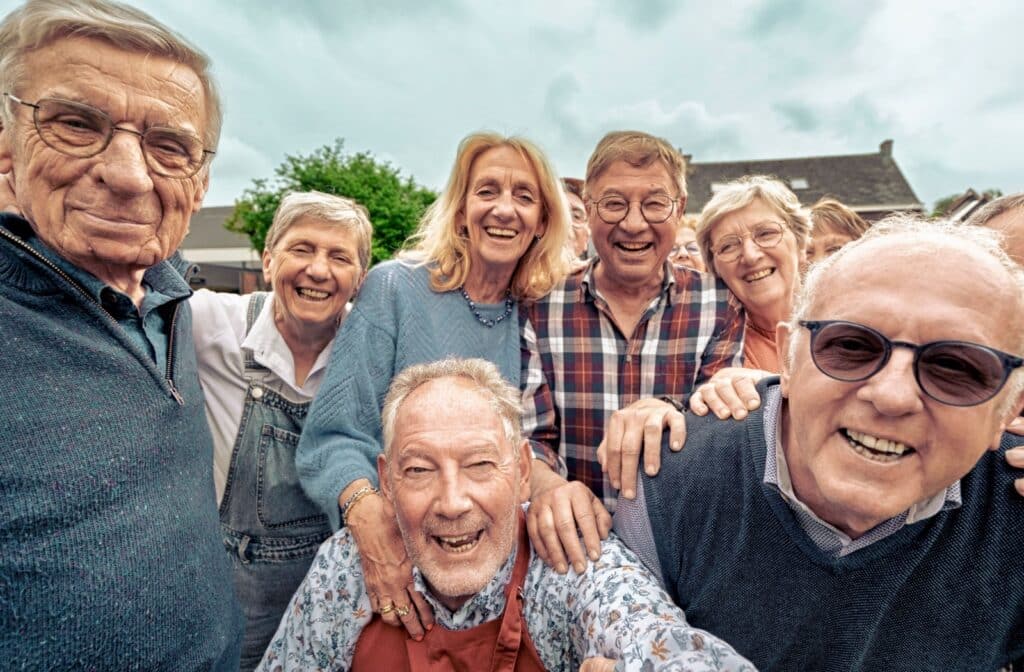 A diverse group of assisted living community members smile together for a photo.