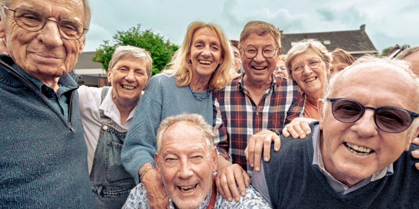 A diverse group of assisted living community members smile together for a photo.