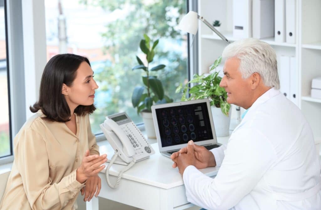 An adult child talks to a neurologist in their well-decorated office after the doctor examined their older parent