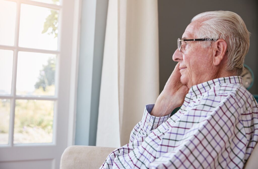 A senior looks out a window, thinking about something nice.